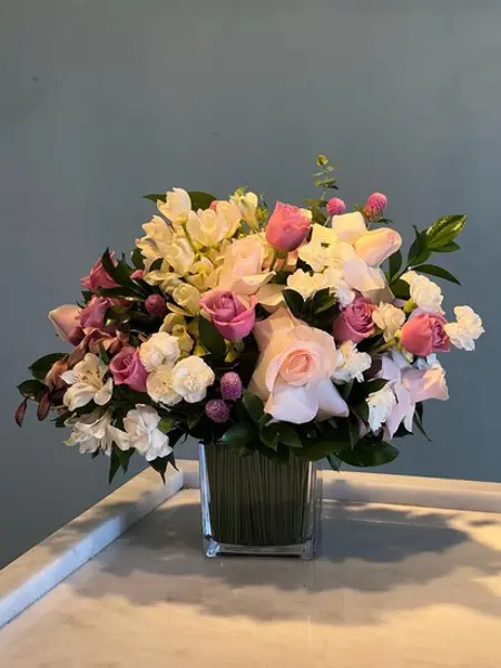 ARRANJO FLORAL EM PEÇA CUBO DE VIDRO.