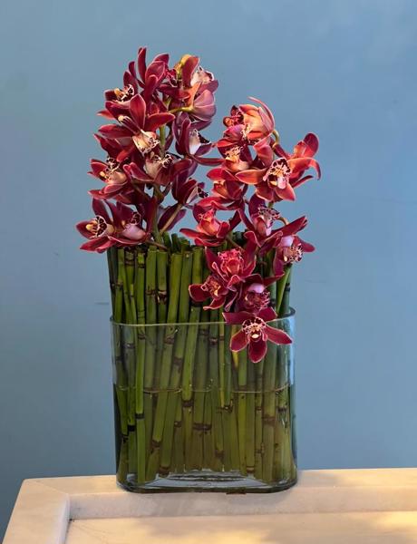 ARRANJO EM VASO DE VIDRO COM ORQUÍDEAS CIMBIDIUM.